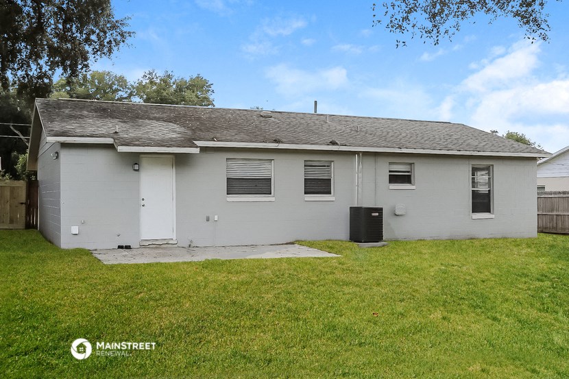 the front of a white house with a yard and grass