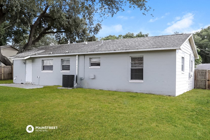 a small white house with a yard and a tree