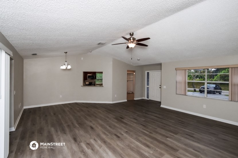 an empty living room with a ceiling fan and a window