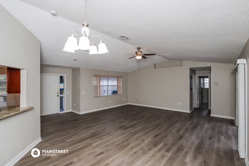 an empty living room with a ceiling fan
