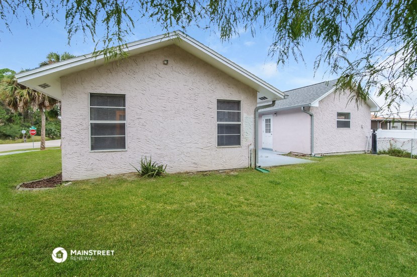 a small white house with a lawn and a tree