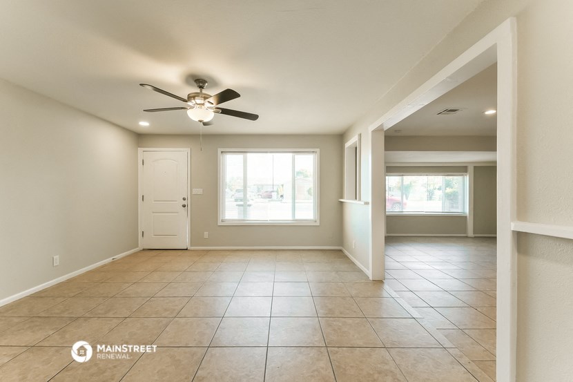 an empty living room with a ceiling fan