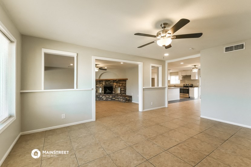 an empty living room with a ceiling fan and a fireplace