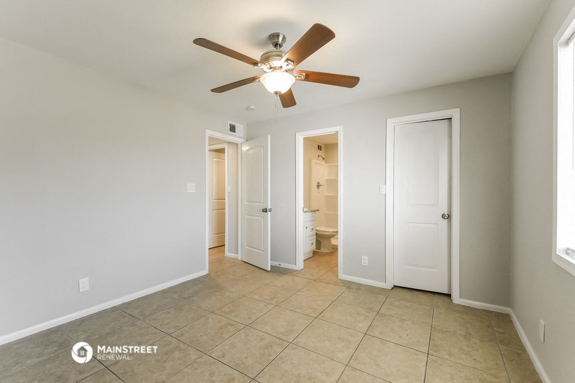 a living room with a ceiling fan and a door to a bathroom
