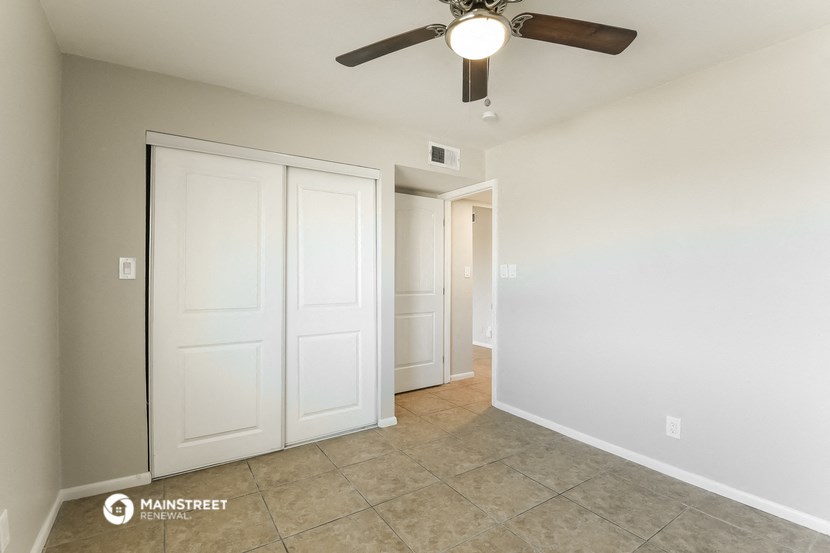 an empty room with a ceiling fan and a closet