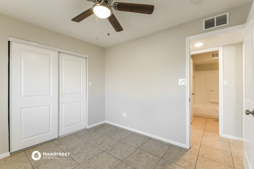 a bedroom with a ceiling fan and a door to a bathroom