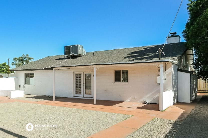 a small white house with a gray roof and a driveway