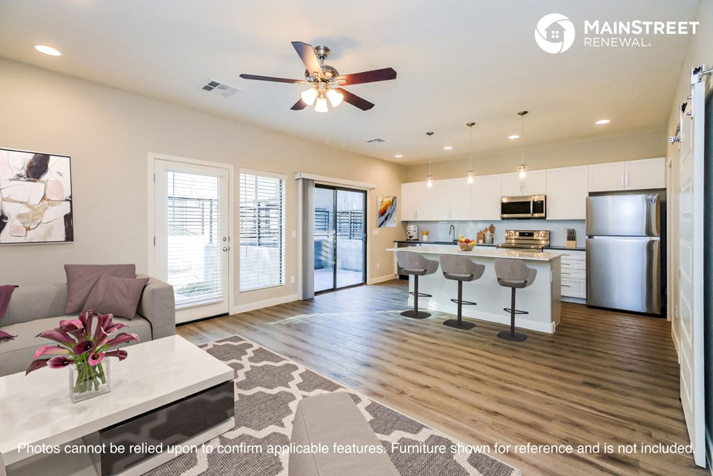 a living room with a kitchen and a ceiling fan