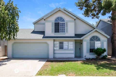 a white house with a gray roof and a tree