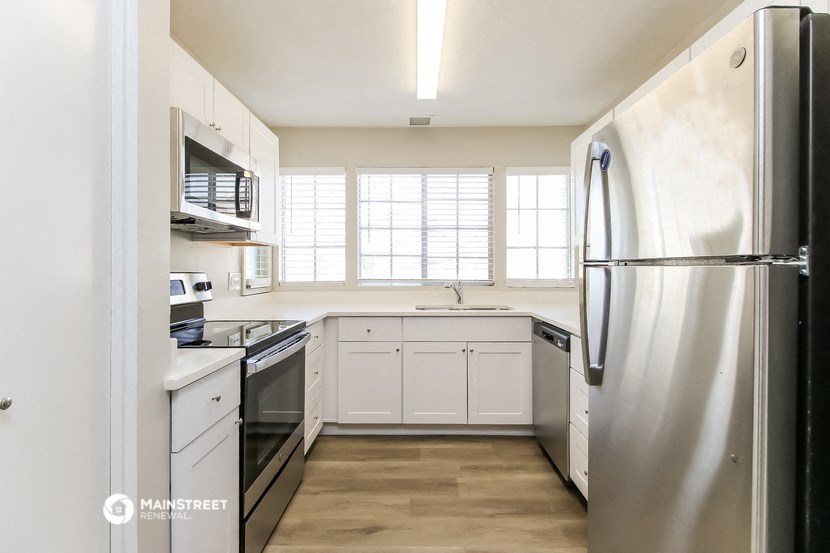 an empty kitchen with stainless steel appliances and white cabinets