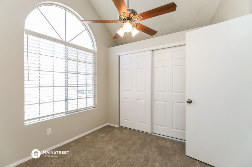 the master bedroom has a large arched window and a ceiling fan