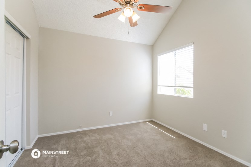an empty room with a ceiling fan and a window