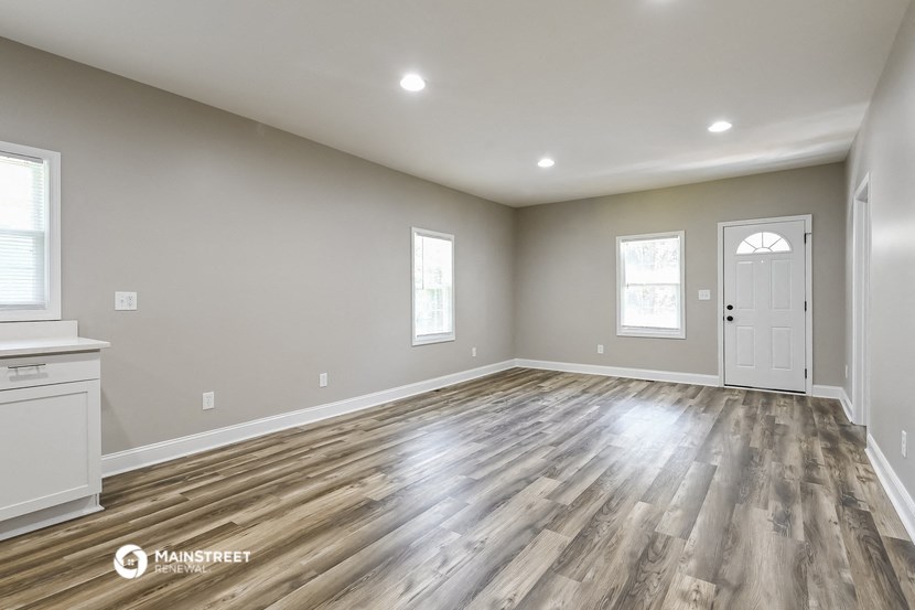 an empty living room with wood flooring and a white door