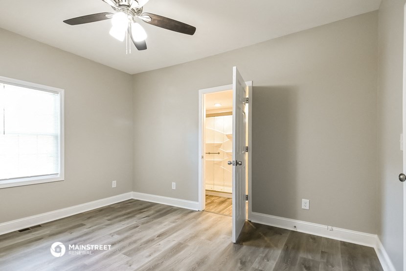 a bedroom with a ceiling fan and a door to a bathroom