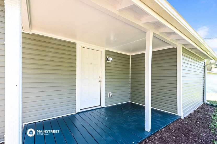 the front of a house with a porch and a white door