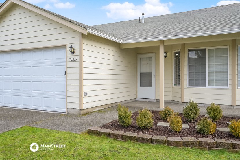 the front of a white house with a white garage door