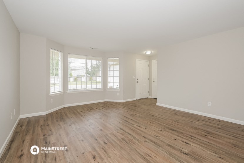 the living room of a new home with wood flooring and white walls