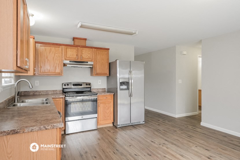 an empty kitchen with wooden cabinets and stainless steel appliances