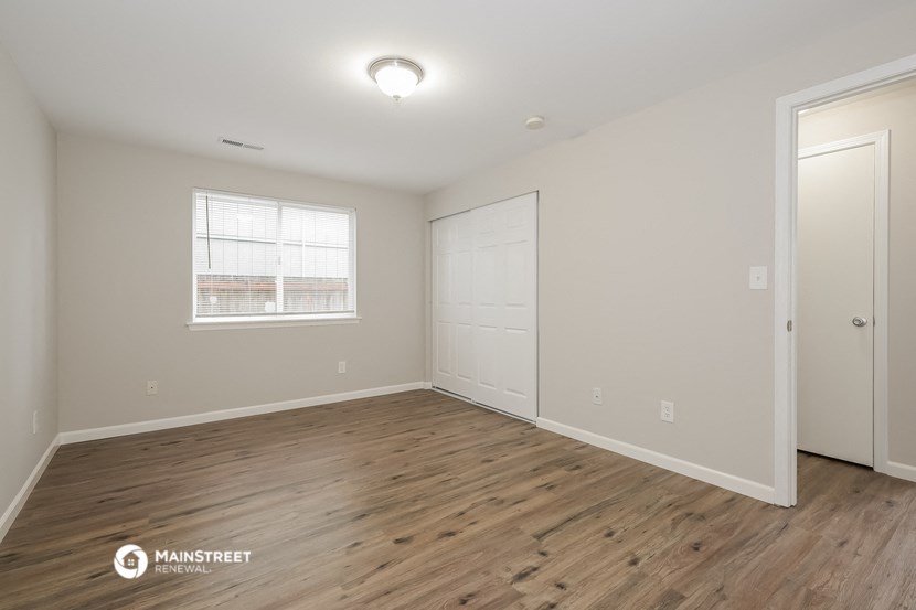 the spacious living room with wood flooring and a window