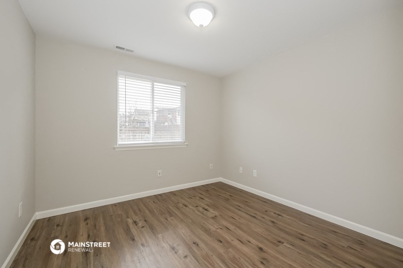 the spacious living room with wood flooring and a window