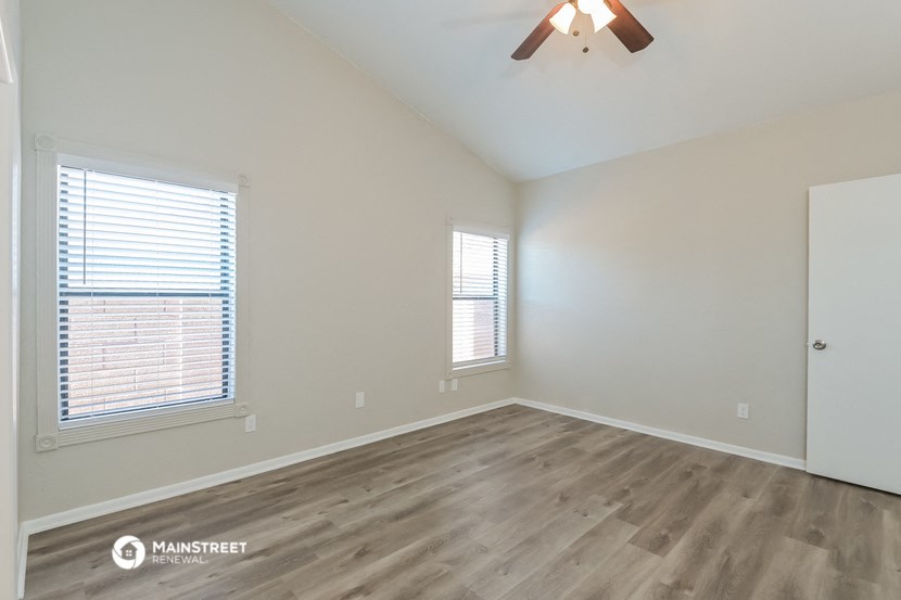 an empty living room with wood flooring and a ceiling fan