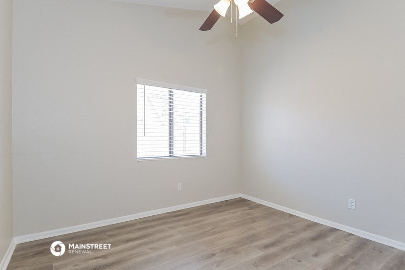 an empty room with a window and a ceiling fan