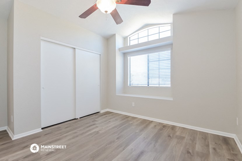 an empty living room with a ceiling fan and a window
