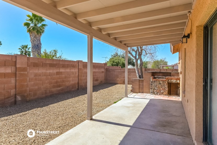 a covered patio in a backyard with a fire pit