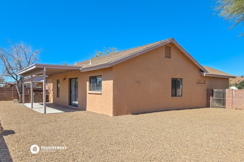 a brown house with a dirt yard and a patio