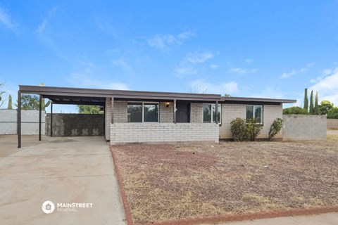 a small brick house with a driveway and a patio