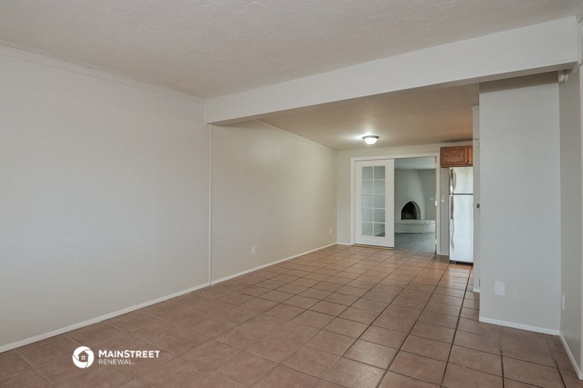 an empty living room with a tile floor and white walls