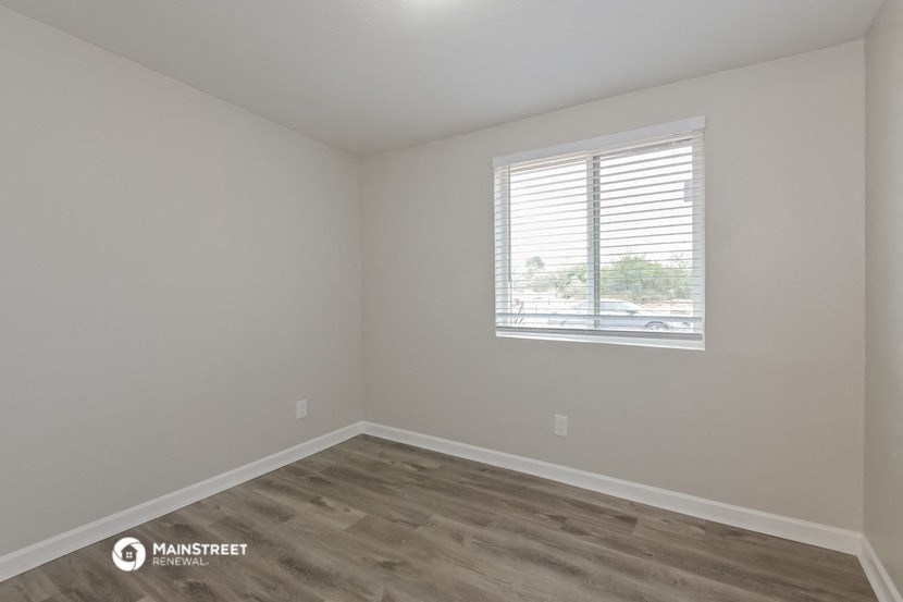 an empty room with a window and wooden floors