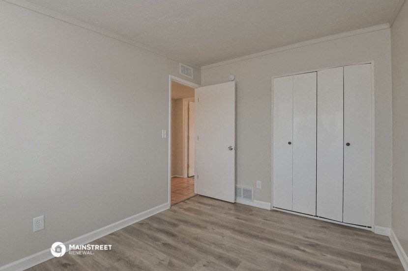 the living room of an apartment with white walls and wood floors