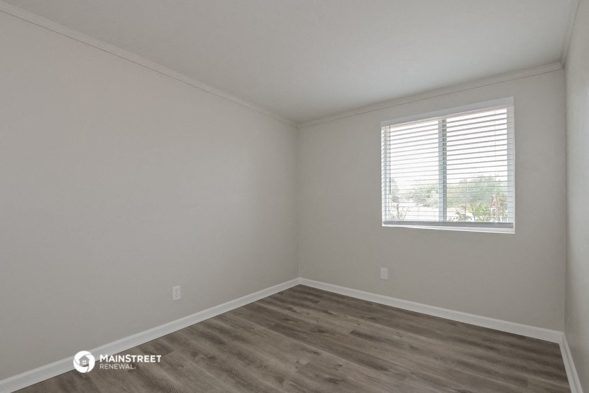 the living room of a house with wooden floors and a window