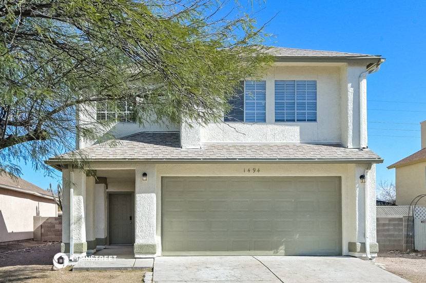 a white house with a garage door and a tree