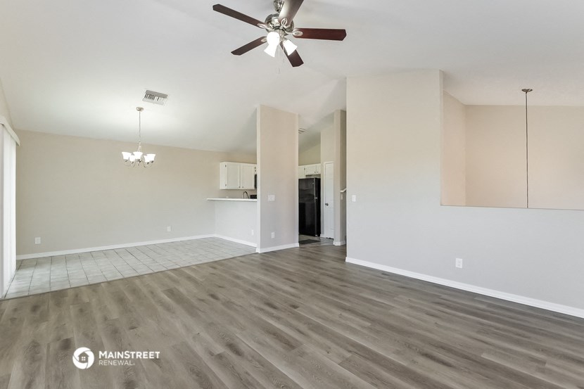 an empty living room with wood flooring and a ceiling fan
