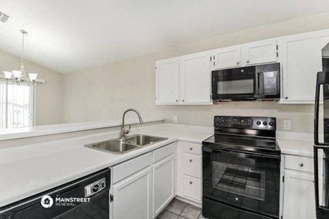 a kitchen with white cabinets and black appliances