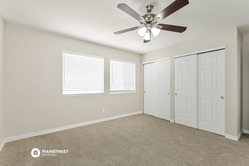 the bedroom has a ceiling fan and two closets