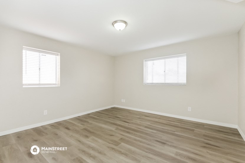 the spacious living room with wood flooring and two windows