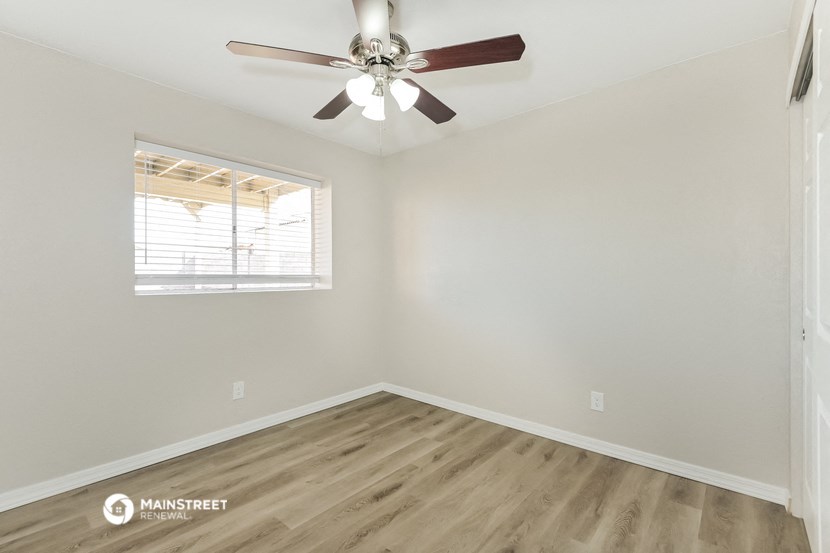 an empty room with a ceiling fan and a window