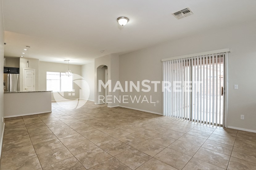 a large living room with tile flooring and a door to a kitchen