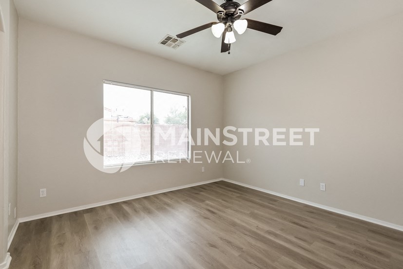 a bedroom with a large window and a ceiling fan