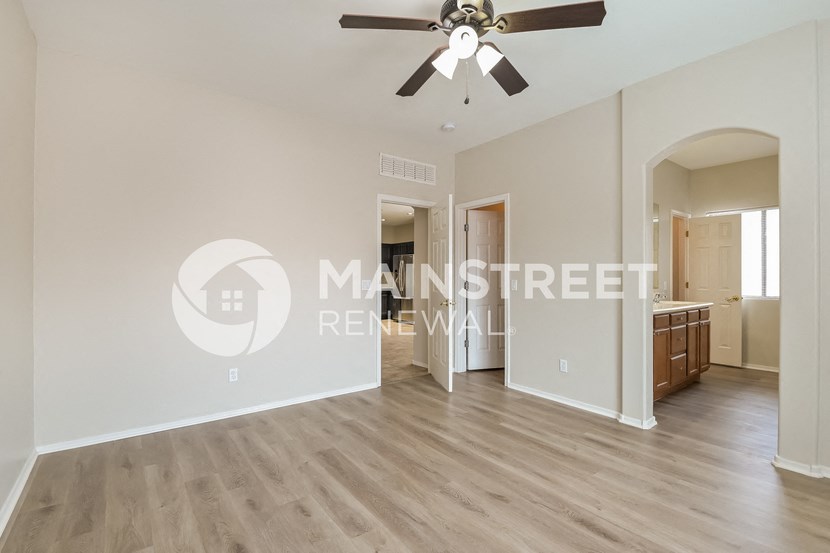 a renovated living room with hardwood floors and a ceiling fan