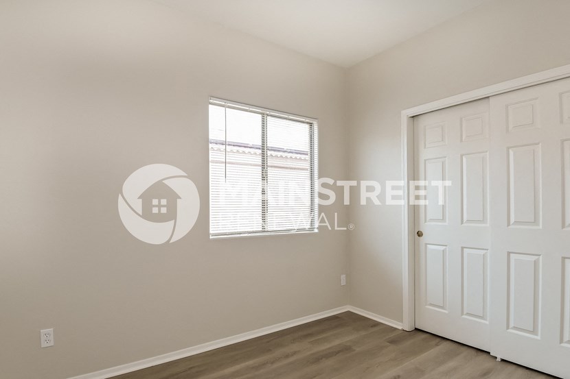 a bedroom with a closet and a white door and a window