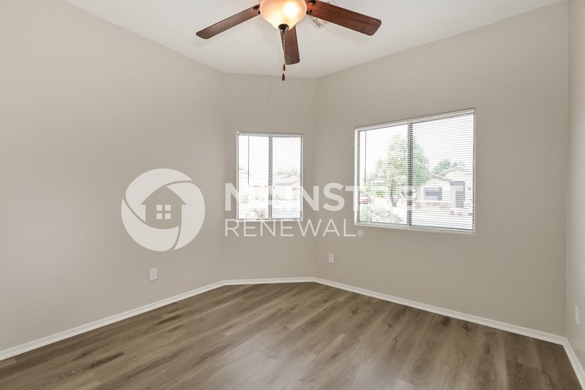 a bedroom with a large window and a ceiling fan