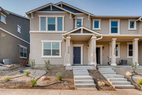 a beige house with steps and a blue door
