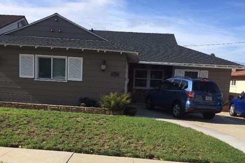 A blue car is parked in front of a house.