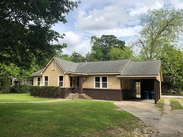 a brown house with a yard and a driveway