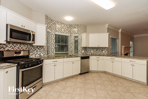 A kitchen with white cabinets and a black stove top oven.