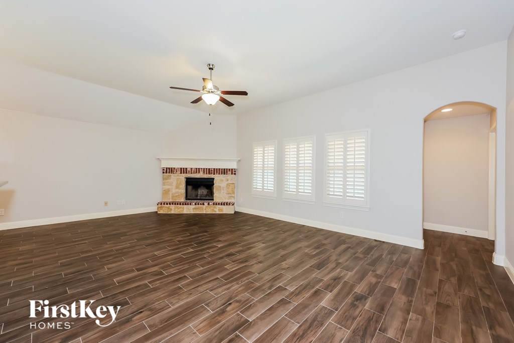 A spacious room with a fireplace and wood flooring.